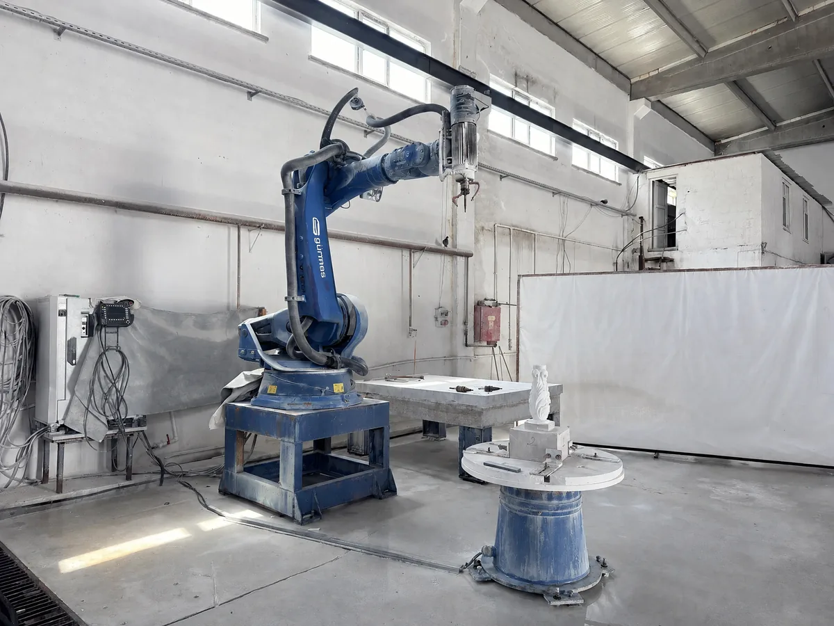 Industrial robot arm carving a marble piece on a rotary table
